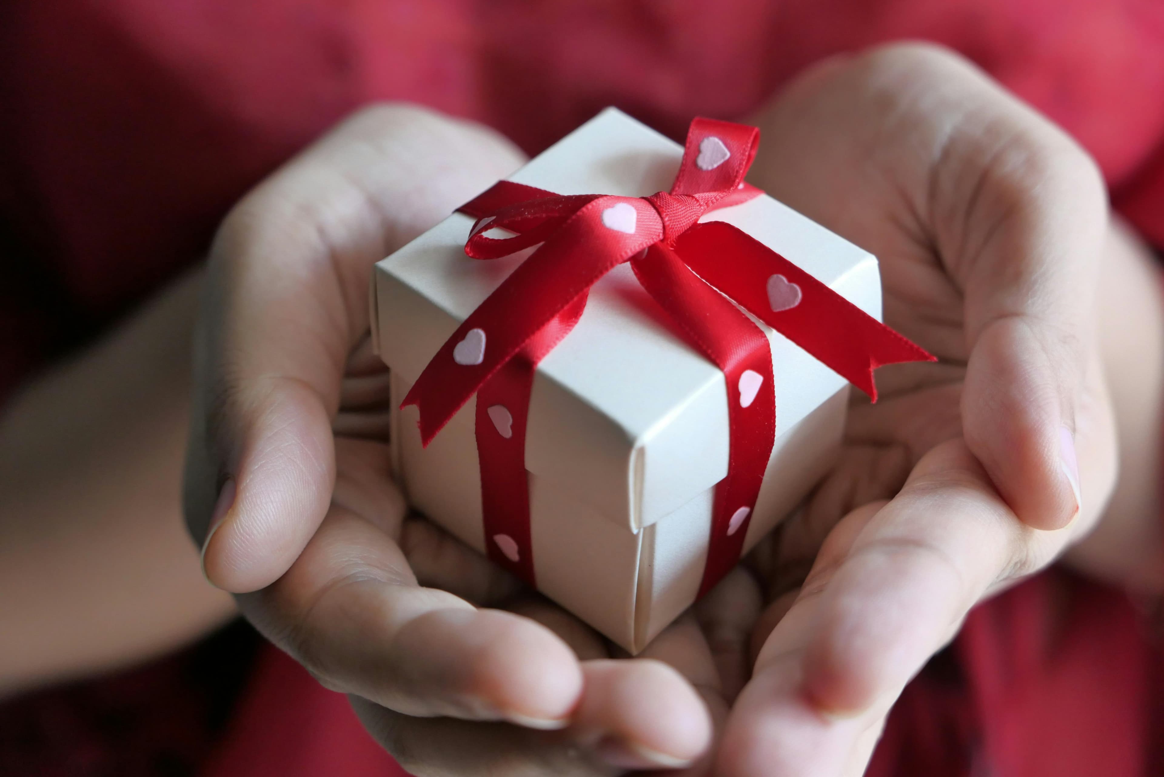 Close-up of someone holding a small wrapped gift box with a ribbon—thoughtful, premium gifting moment